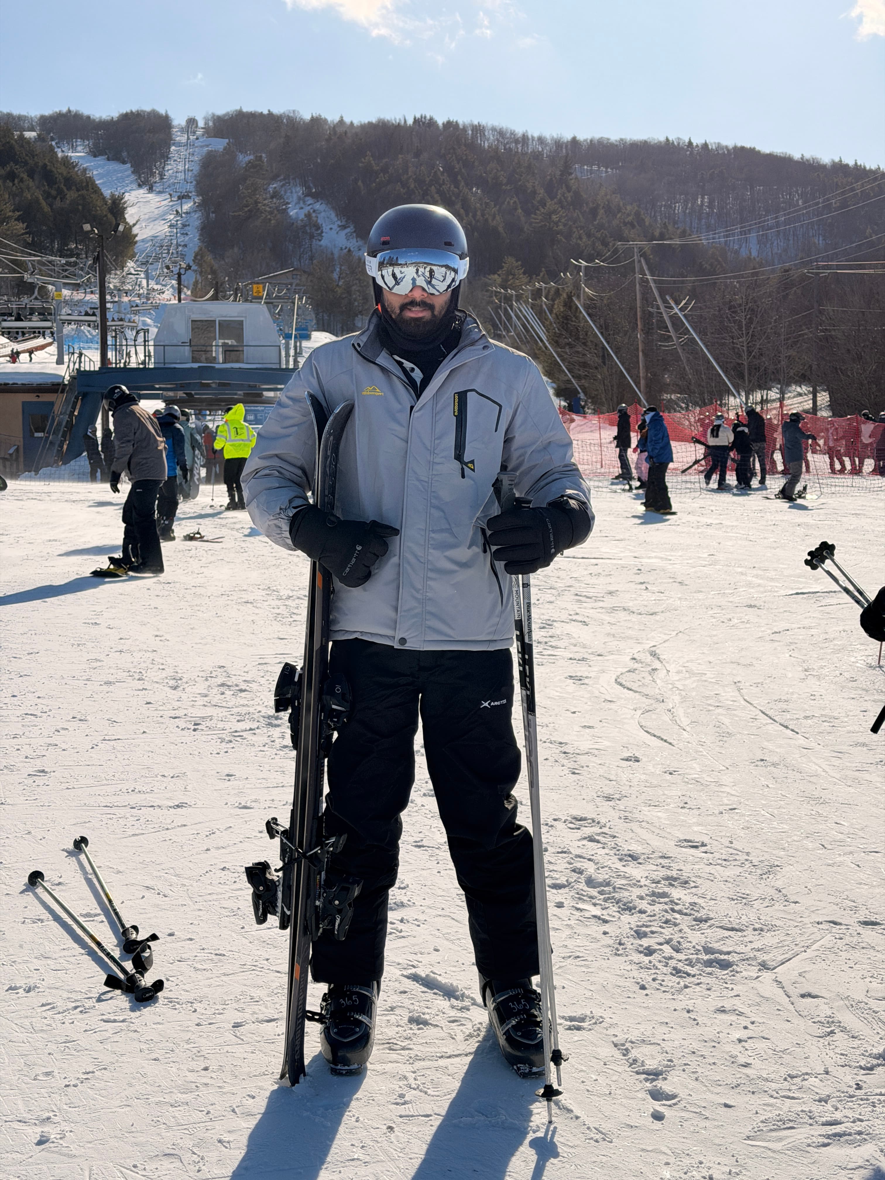 Full-length portrait in ski gear on a sunny mountain slope with a ski lift behind