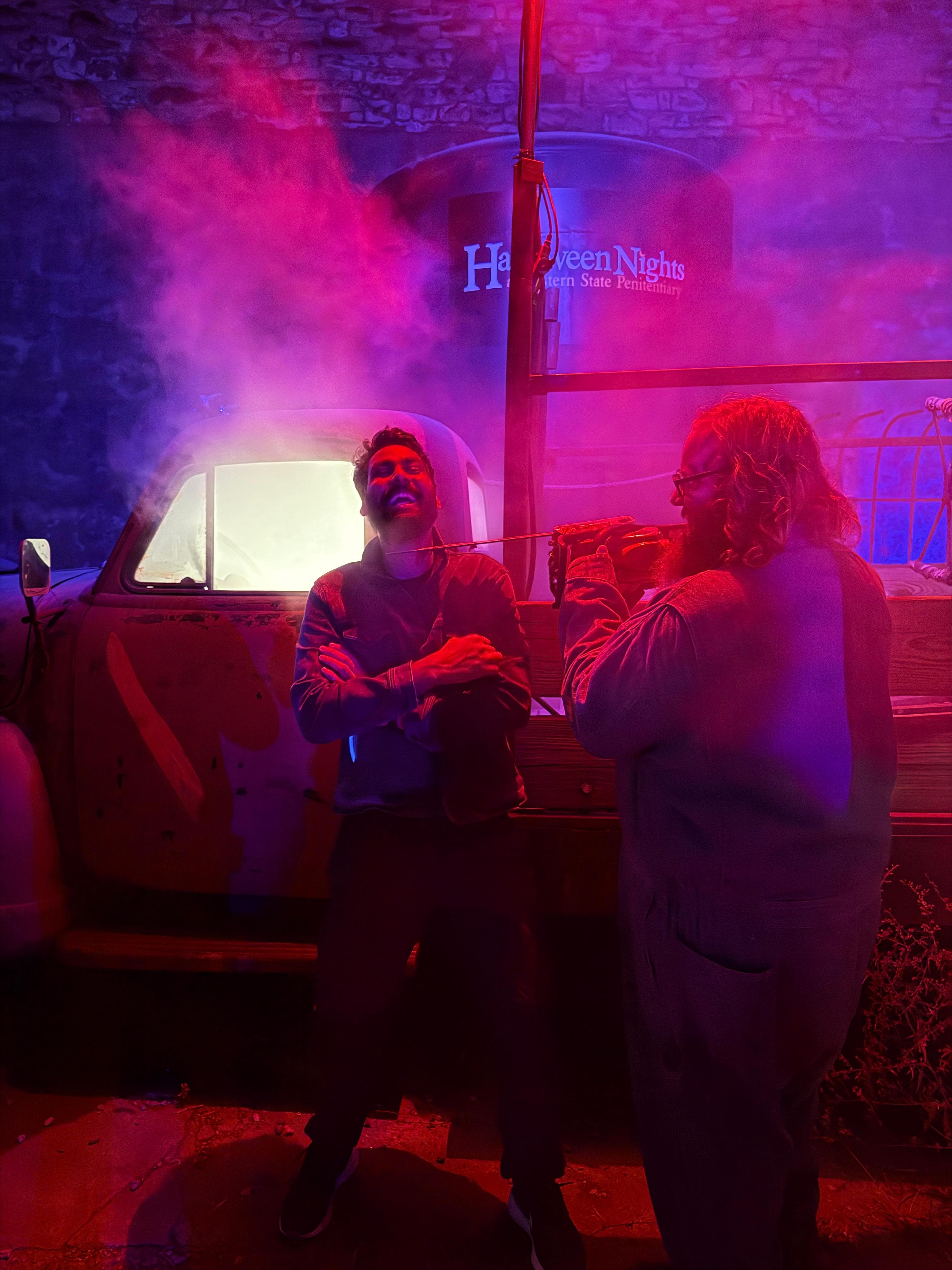 Two friends posing under red fog lights at Halloween Nights at Eastern State Penitentiary
